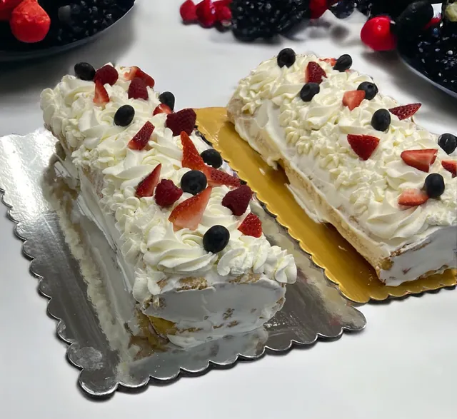 Two cream roll cakes topped with strawberries and blueberries