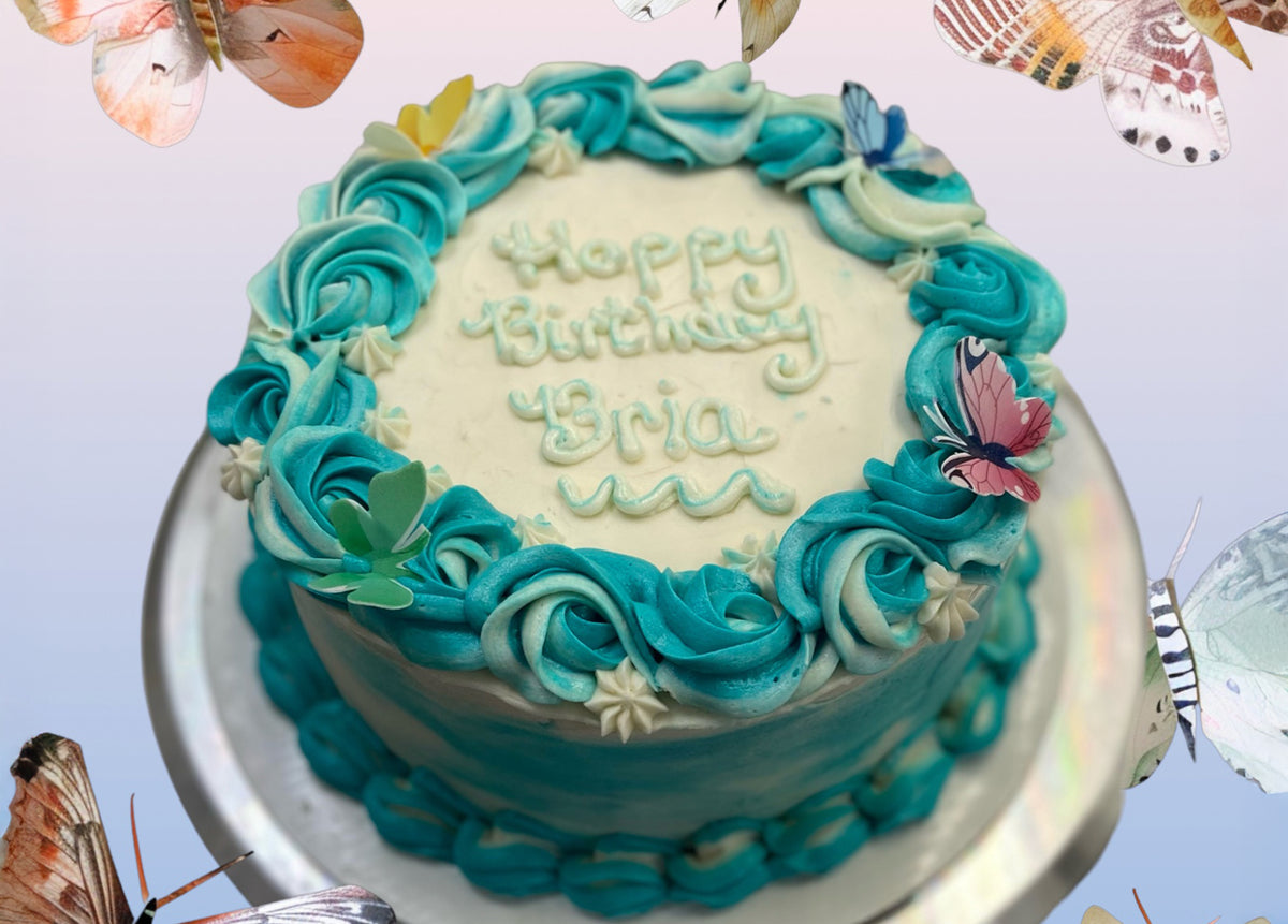 A birthday cake ringed with teal and white buttercream rosettes