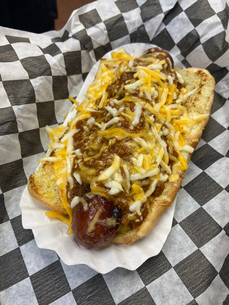 A hot dog under chili and shredded cheese on a toasted bun