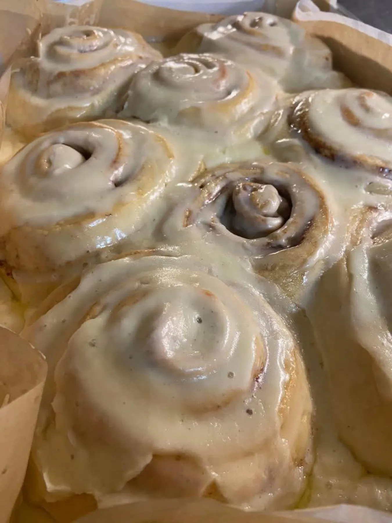 Iced cinnamon rolls packed into a paper-lined pan