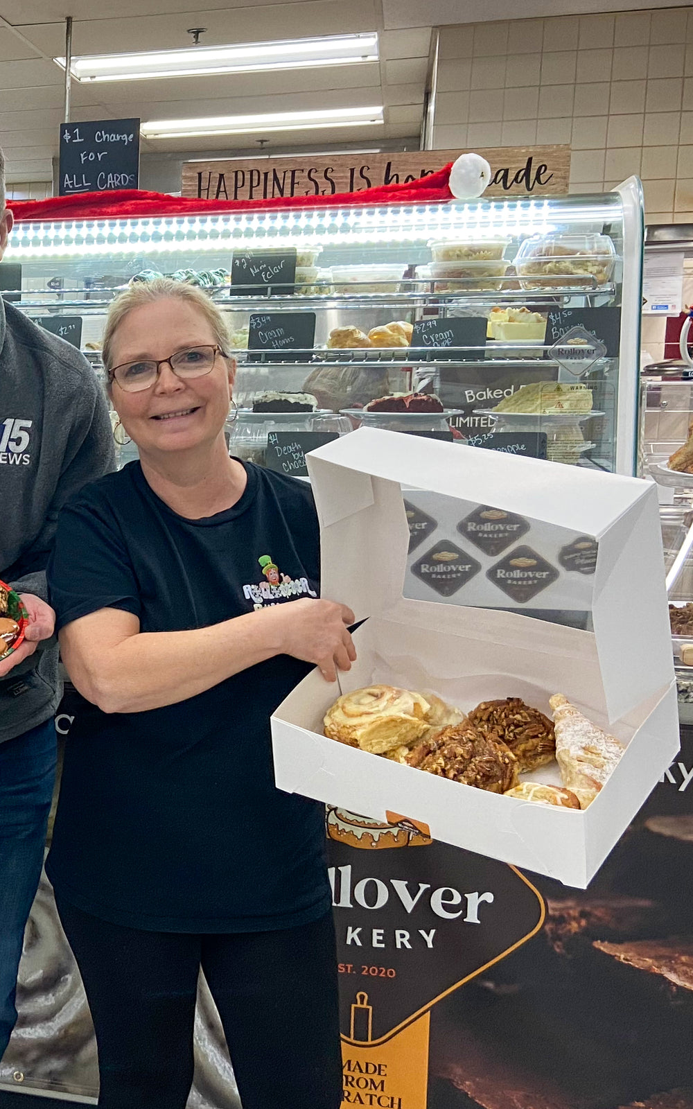 At the Rollover counter, holding open a box of cinnamon rolls and pecan sticky buns in front of the pastry case