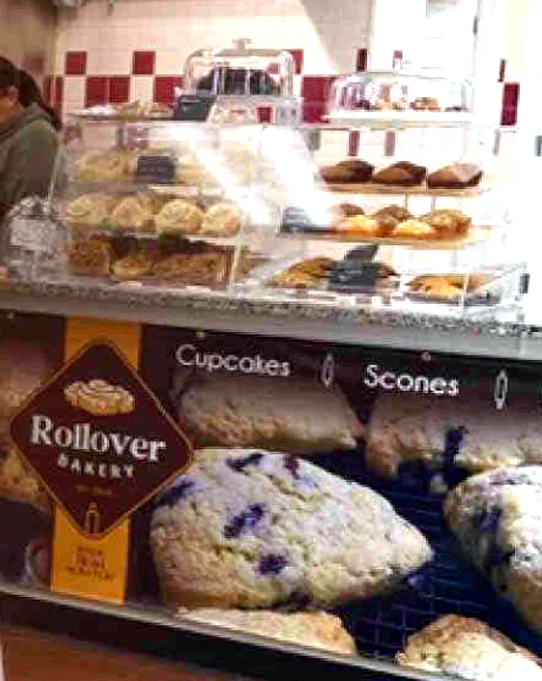 The Rollover counter inside the flea market: glass shelves of muffins and pastries above a case of scones, with the black-and-gold Rollover badge on the front