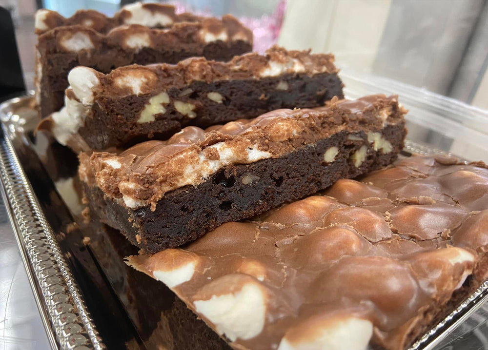 Thick brownies topped with marshmallow and chocolate, stacked on a tray
