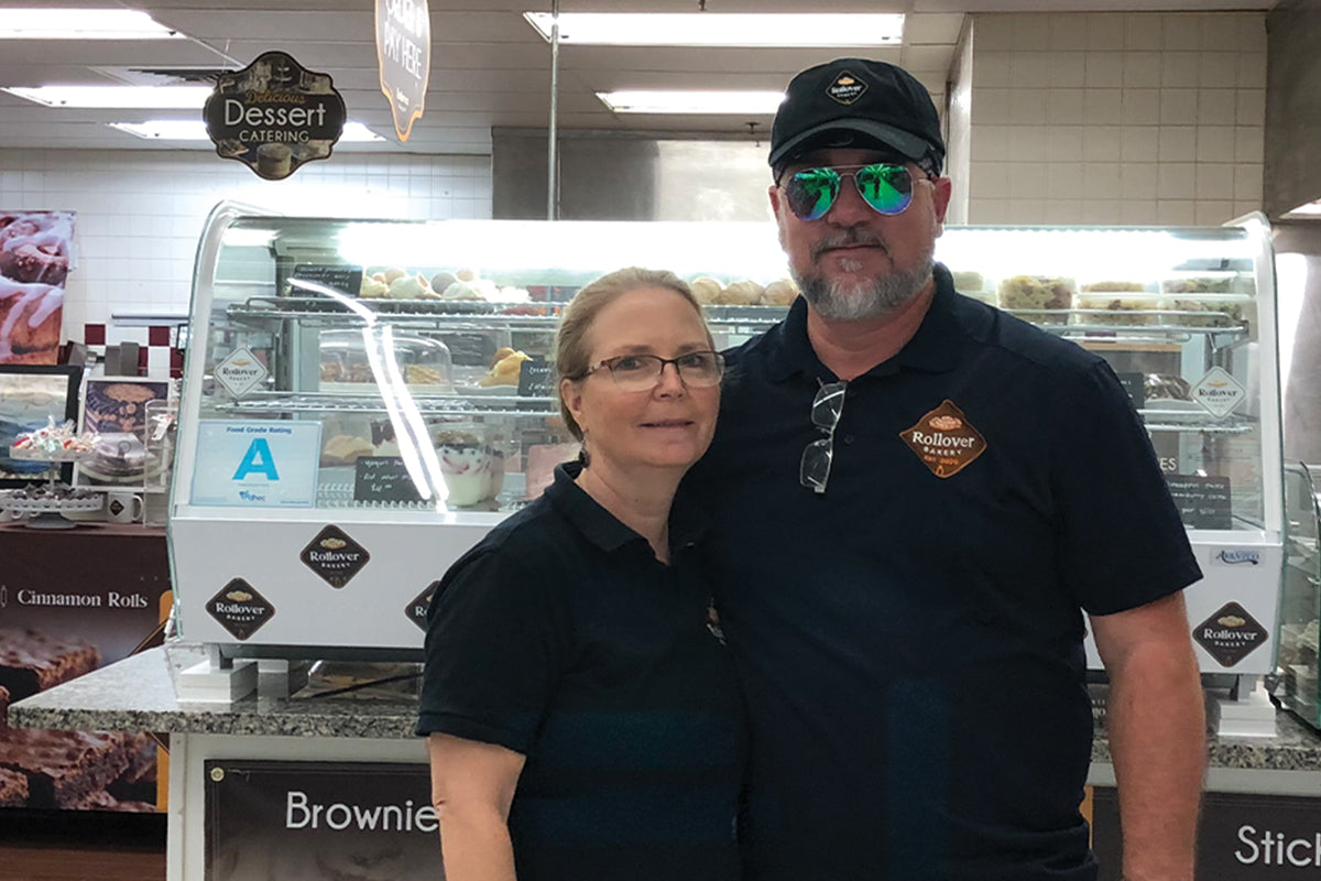 Two people in Rollover Bakery shirts standing in front of the bakery’s pastry case