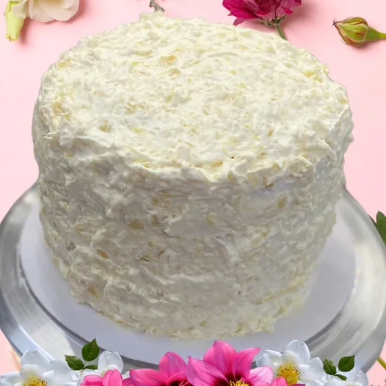 A tall white layer cake with textured frosting on a glass stand